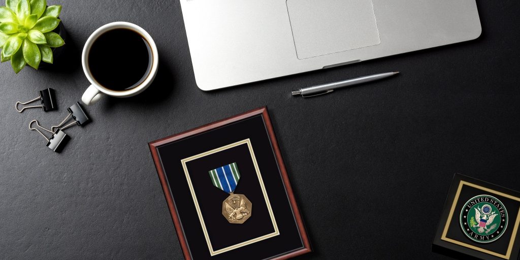 Army achievement award and Army paperweight on desk