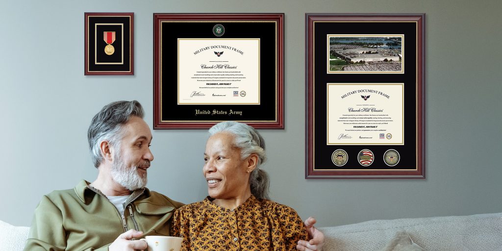 retired veretan sitting on couch with spouse in front of wall of custom military frames and awards