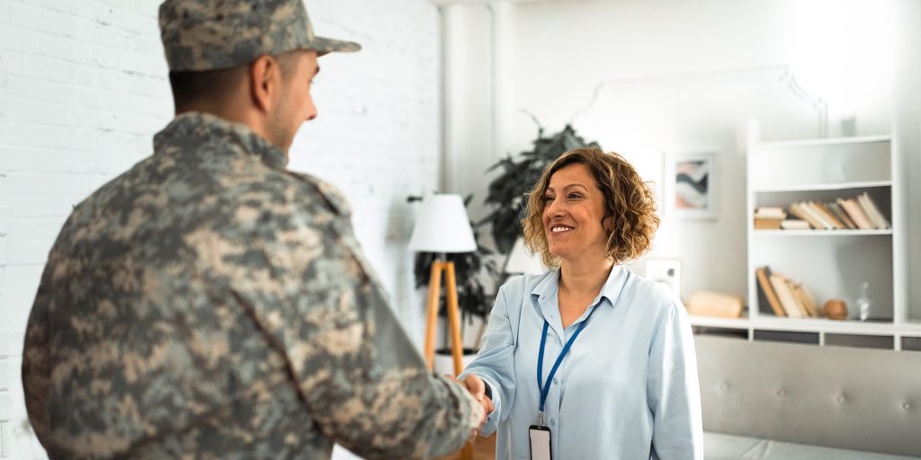 woman smiling and shaking the hand of a service member