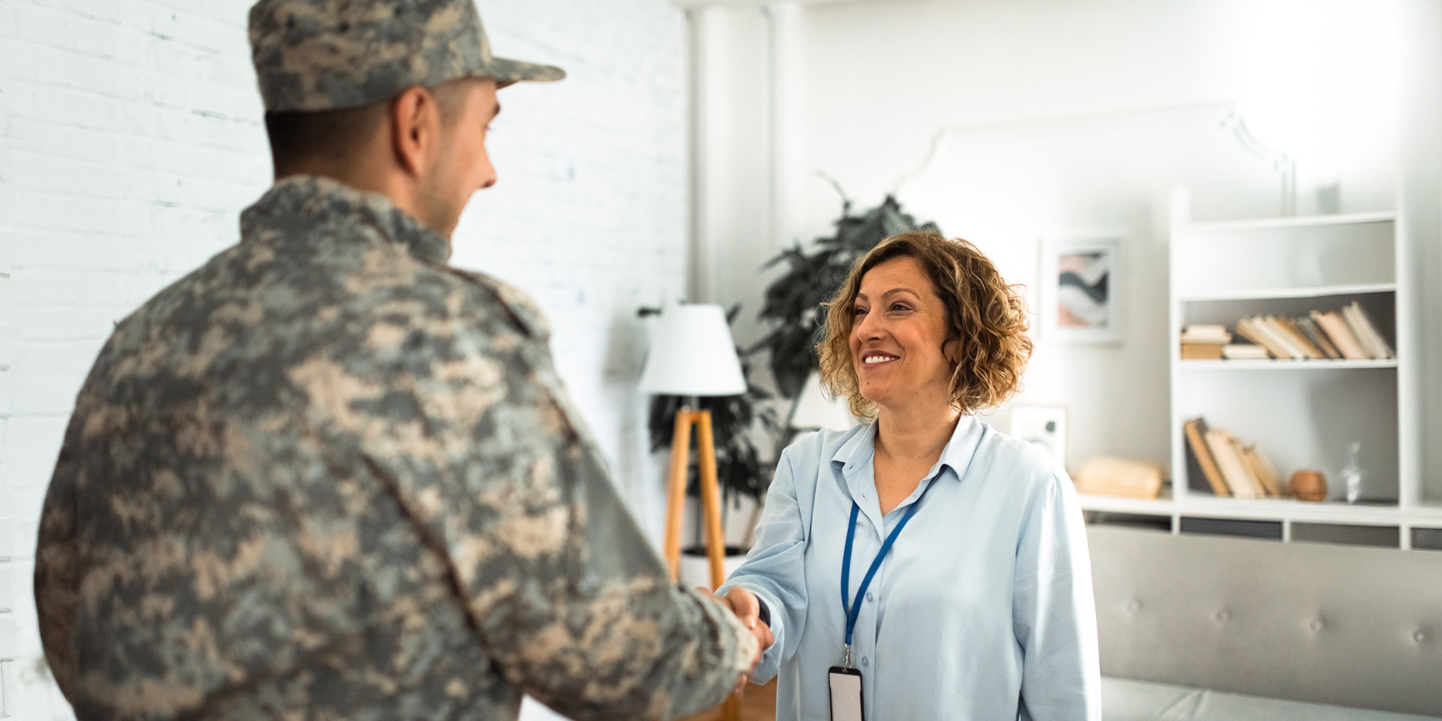 woman smiling and shaking the hand of a service member