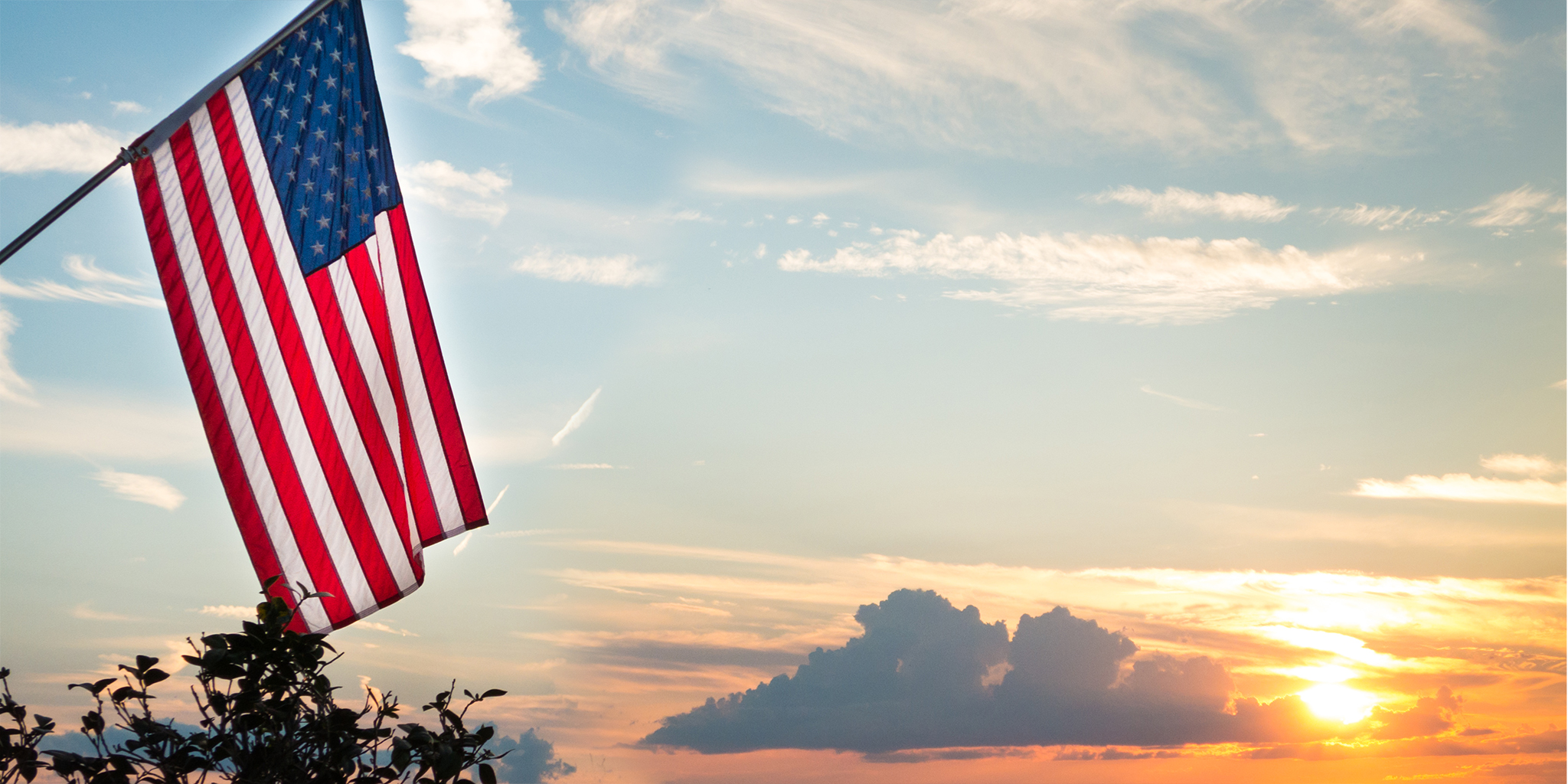 American flag flying outside in front of a sunset