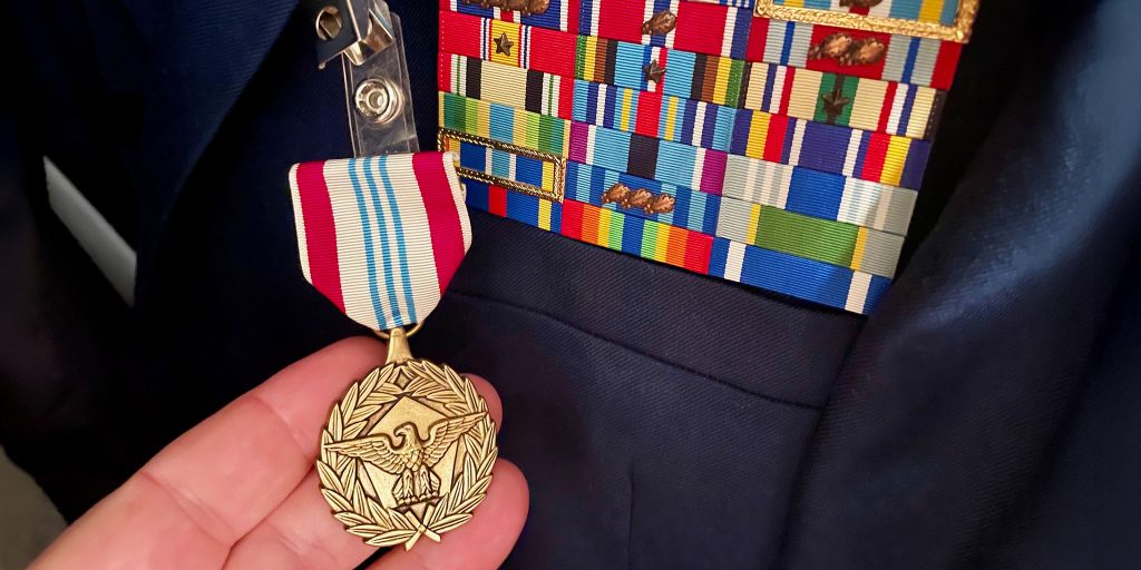 hand holding military medal in front of military jacket